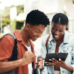 Student happily applying online for the Too Cool to Pay for School Scholarship on a laptop.
