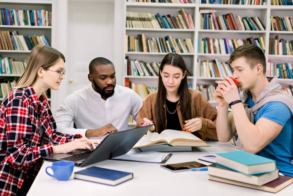 Diverse group of students collaborating at library table researching St. Francis High School Wheaton Illinois scholarships and financial aid.