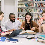 Diverse group of students collaborating at library table researching St. Francis High School Wheaton Illinois scholarships and financial aid.